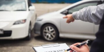 Cropped hand of insurance agent by customer gesturing at car