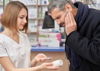 Pharmacist helping man with tooth ache in drugstore.