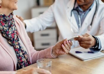 Closeup of a doctor giving pills to senior woman during home visit