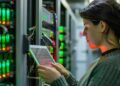 A woman in a data center configuring a server while referencing data on a tablet
