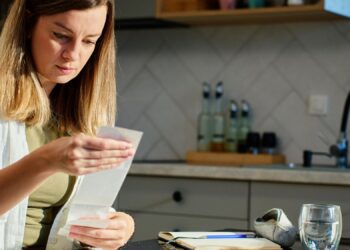 Woman planning home budget analyzing financial bills in kitchen