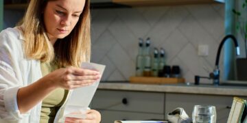 Woman planning home budget analyzing financial bills in kitchen