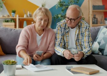 Elderly couple looking at bills and phone