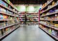 young man with shopping cart between store shelf grocery