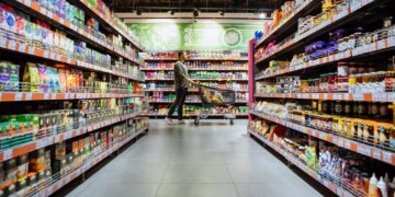 young man with shopping cart between store shelf grocery