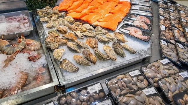 Fresh seafood display with various shrimps salmon fillet oysters clams shellfish in grocery store