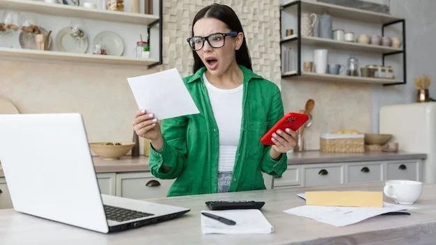 Shocked young woman reading a received letter while sitting in the kitchen at home he holds the